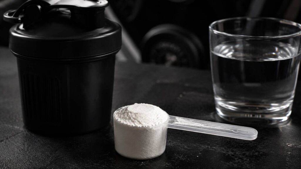 dose de 5g de créatine monohydrate mesurée avec une cuillère doseuse sur un plan de travail de home gym