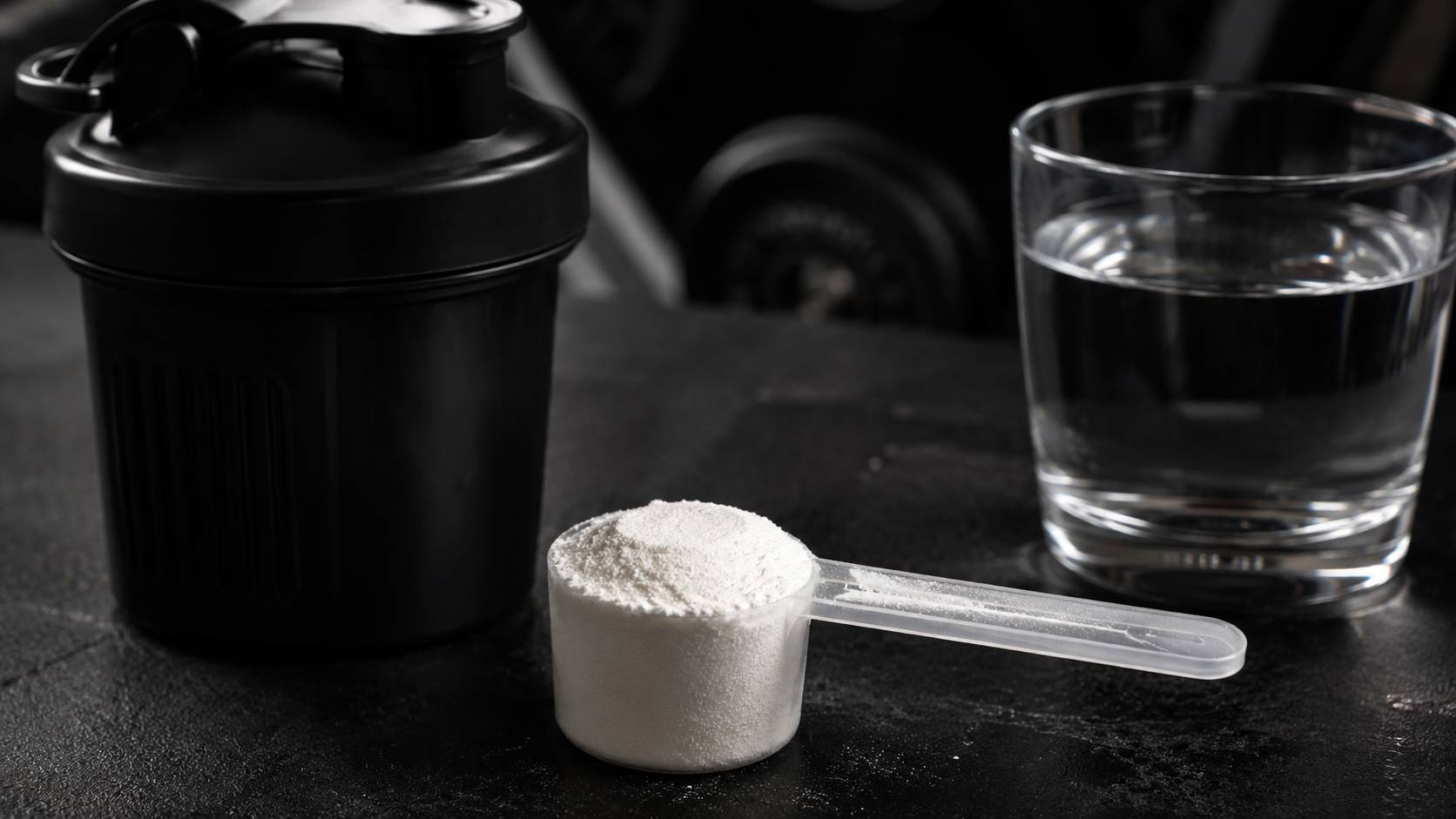 dose de 5g de créatine monohydrate mesurée avec une cuillère doseuse sur un plan de travail de home gym