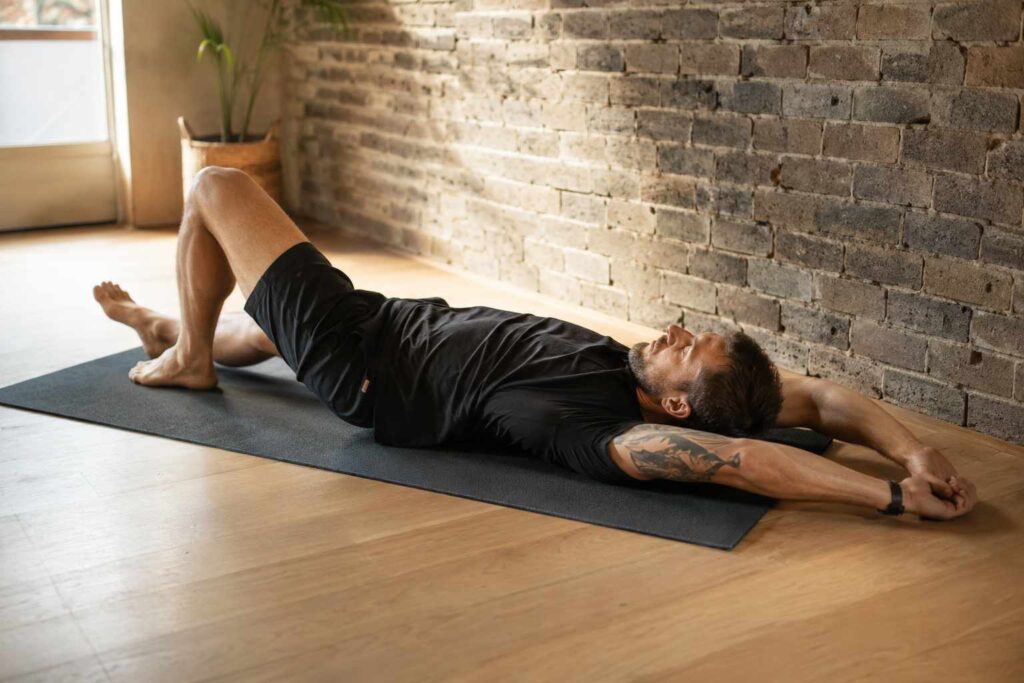 Homme s'étirant sur tapis de sol dans un home gym le matin — protocole récupération musculation